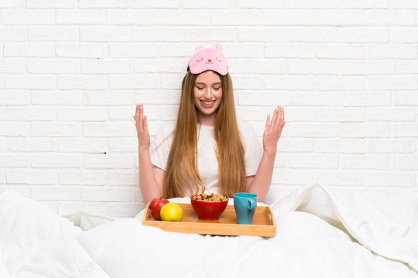 Young woman in dressing gown with breakfast laughing - Foto, afbeelding