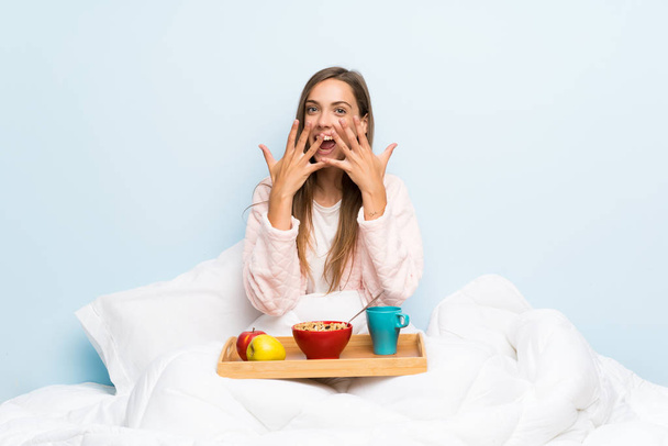 Young woman in dressing gown with breakfast with surprise facial expression - Foto, immagini