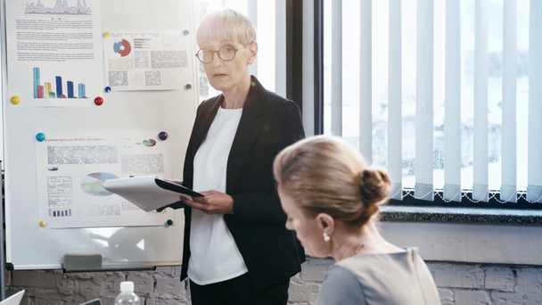 rack focus de femme d'affaires dans des lunettes geste tout en parlant près de beau collègue au bureau
  - Séquence, vidéo