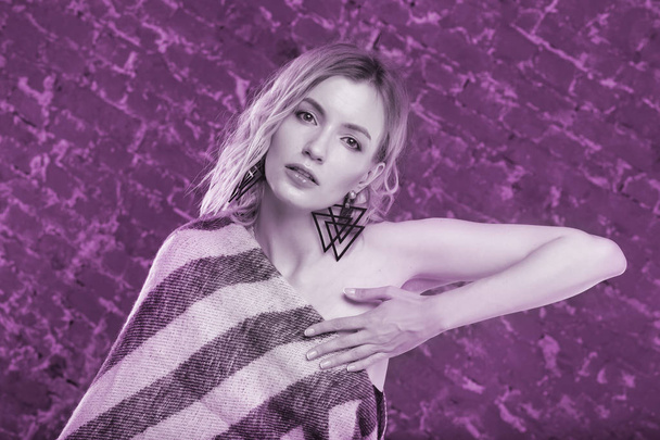 Portrait of a young sexy female fashion model in wool blanket on brick wall background. Photo tinted in purple. - Fotografie, Obrázek