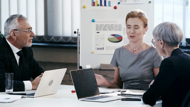 gelukkige zakenvrouw glimlachend en gebaren tijdens het praten met collega's in Office  - Video