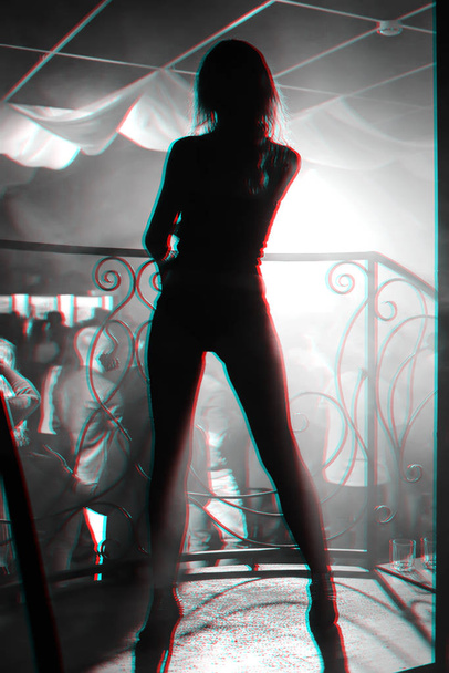 silhouette of a young slim sexy girl in nightclub - Фото, зображення