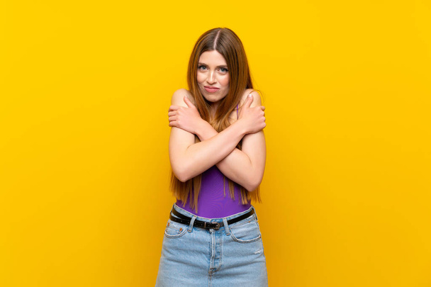 Young woman over isolated yellow background freezing - Foto, Bild
