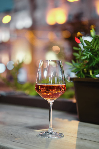 Glass of rose wine on bar counter with night city view on bacground - 写真・画像