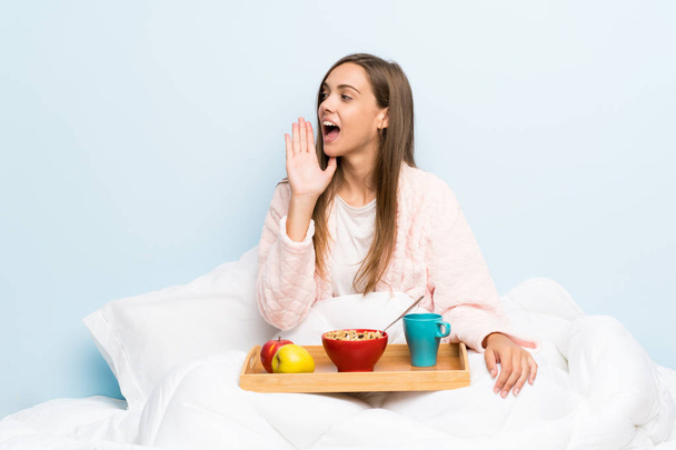 Młoda kobieta w szlafroku ze śniadaniem krzycząc z szeroko otwartymi ustami - Zdjęcie, obraz