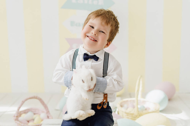 Sonriente chico caucásico jugando con conejo de Pascua
 - Foto, imagen