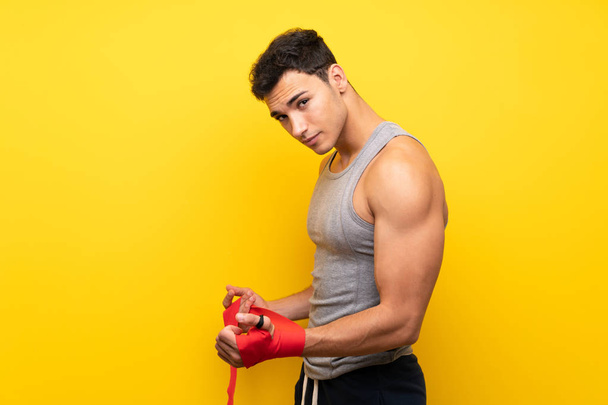 Handsome sport man over isolated background in boxing bandages - Фото, зображення