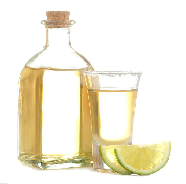 Gouden Tequila in een glas met zout en limoen op een witte geïsoleerde achtergrond. alcoholische dranken. Close-up. - Foto, afbeelding