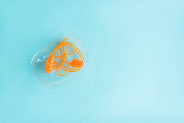 pair of orange rubber earplugs in the form of spruce lie in a box on a blue background - Фото, зображення