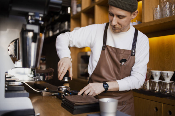 barbudo feliz barista preparando café en la cafetería. Barista profesional, proceso de trabajo
 - Foto, imagen