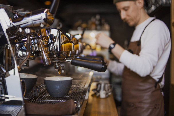 бородатый счастливый бариста готовит кофе в кафе магазин. Профессиональный бариста, процесс работы
 - Фото, изображение