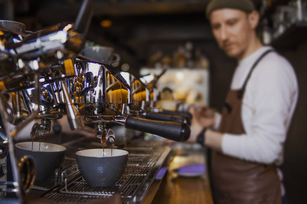 бородатый счастливый бариста готовит кофе в кафе магазин. Профессиональный бариста, процесс работы
 - Фото, изображение