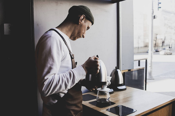 Мужчина Бариста сделать капельное пивоварение, фильтрованный кофе, или залить более является метод, который включает заливки воды на жареный, молотый кофе в зернах, содержащихся в фильтре. в кофейне. Винтажный тон
 - Фото, изображение