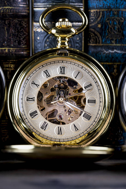 Antique clock on the background of vintage books. Mechanical clo - Fotoğraf, Görsel