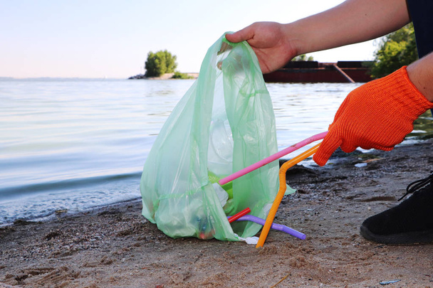 Müllabfuhr am Strand. Plastik und Pakete am Strand verstreut. Ein Mann sammelt Plastik. Umweltschutzkonzept - Foto, Bild