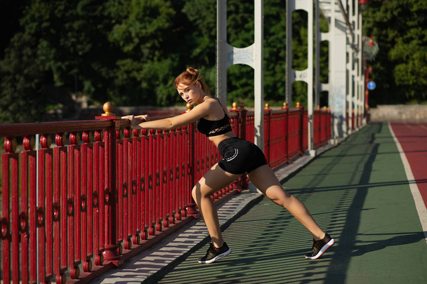 Υπέροχη αθλητική γυναίκα κάνει τέντωμα προπόνηση στη γέφυρα σε  - Φωτογραφία, εικόνα