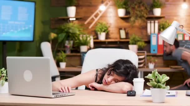 Vrouw op haar werkplek slaapt terwijl haar collega werkt - Video