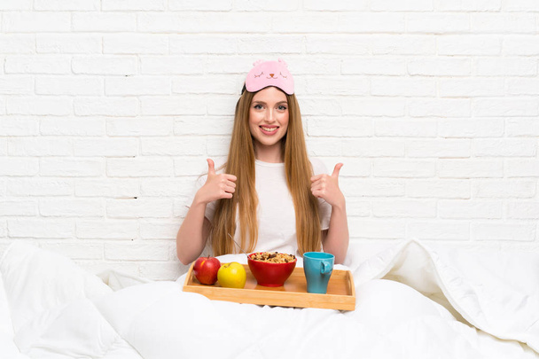 Young woman in dressing gown with breakfast giving a thumbs up gesture - Photo, Image