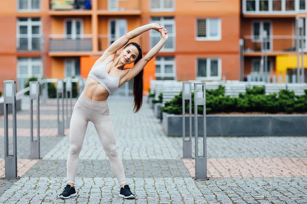 Portrait of young, pretty, fit and sporty young woman doing stretching in city. - Foto, immagini