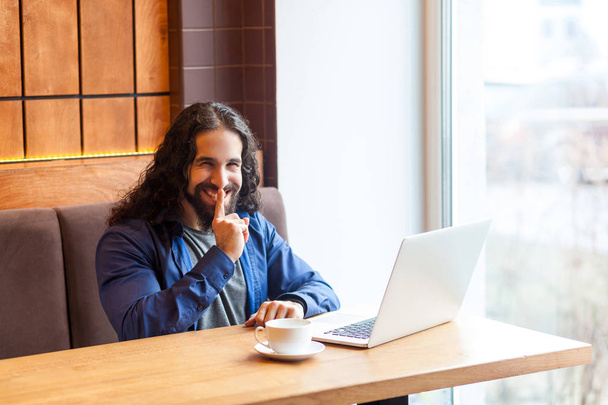 happy handsome intelligence man freelancer in casual style sitting in cafe with laptop and showing shh sign while holding finger near lips  - Фото, зображення