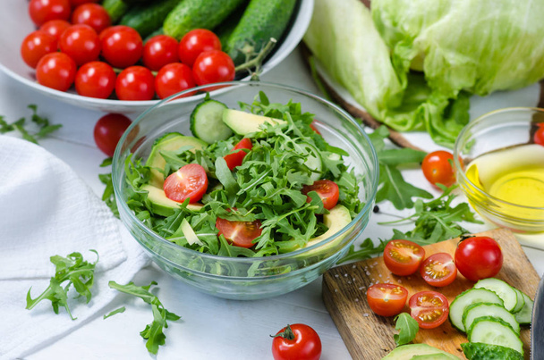 Fresh salad with cucumbers, cherry tomatoes, arugula, avocado, baby corn on white background. Vegetables on wood. Bio Healthy food, herbs and spices. Organic vegetables on wood. - Fotó, kép
