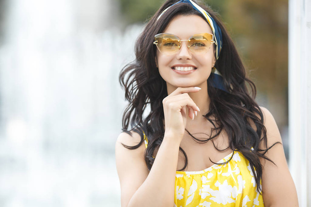Stylová mladá žena ve žlutých slunečních brýlích. Krásný portrét atraktivní ženské venku. Mladá dívka šatna na výšku. - Fotografie, Obrázek