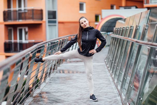 Girl  stretching  in the summer in the city, on the morning run. Stair background. Clothing leggings top. Healthy life. - Photo, image