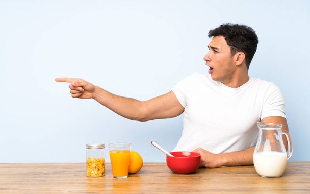 Handsome man in having breakfast pointing finger to the side - Photo, Image