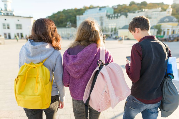 Vista de trás em três estudantes do ensino médio com mochilas
 - Foto, Imagem