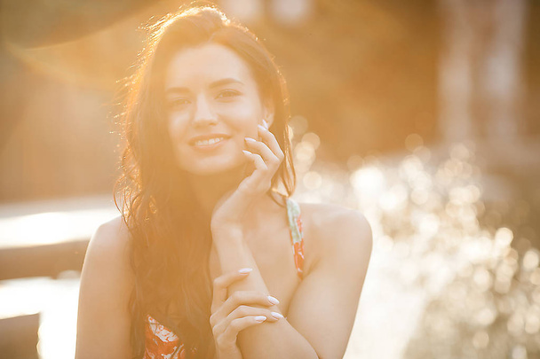 Szépség portréja nő a szabadban. Vonzó stílusos fiatal nő a szökőkút közelében a nyáron. Closeup portré vidám lány. - Fotó, kép