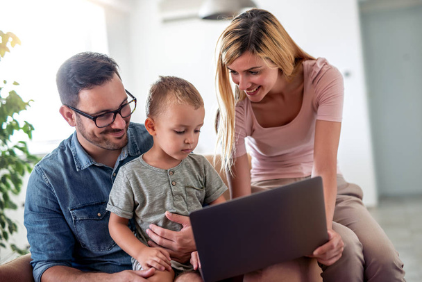 Famiglia giovane che guarda il computer portatile insieme a casa
.  - Foto, immagini