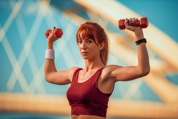 Fitness nő portréja testedzés súlyokkal a városban. - Fotó, kép