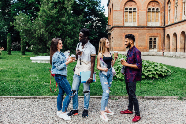 Summer, friendship, education and teenage concept - group of happy students with folders learning and drinking coffee at campus. - Foto, Imagem