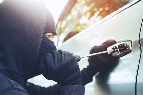 Close up hand pulling the handle of a car thief wearing black clothes and glove stealing automobile trying door handle to see if vehicle is unlocked trying to break into. car theft concept. - Photo, Image