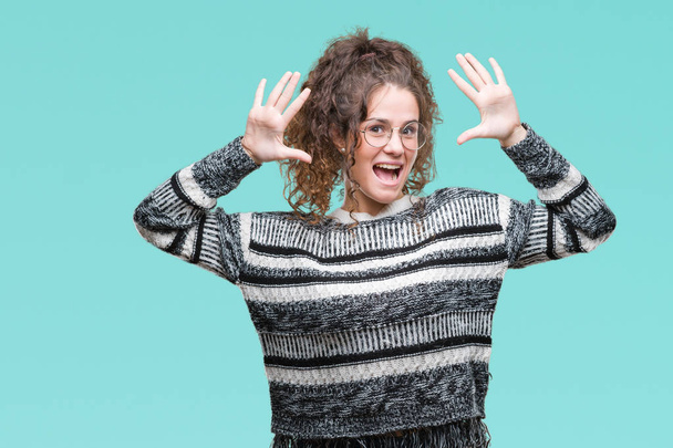 Beautiful brunette curly hair young girl wearing glasses over isolated background showing and pointing up with fingers number ten while smiling confident and happy. - Photo, Image