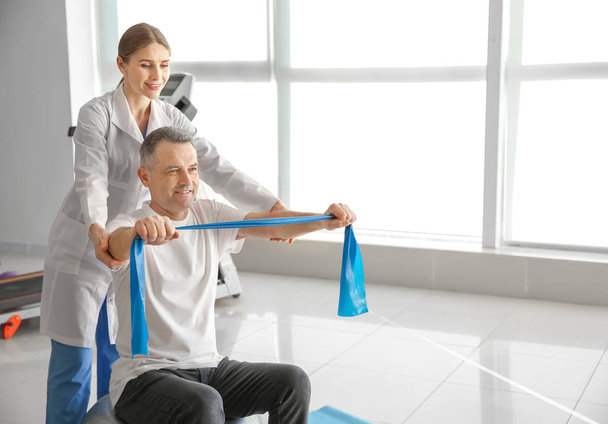 Physiotherapist working with mature patient in rehabilitation center - Foto, imagen