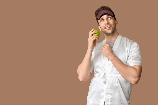 Zabawny młody człowiek z maski snu i jabłko na kolorowym tle - Zdjęcie, obraz