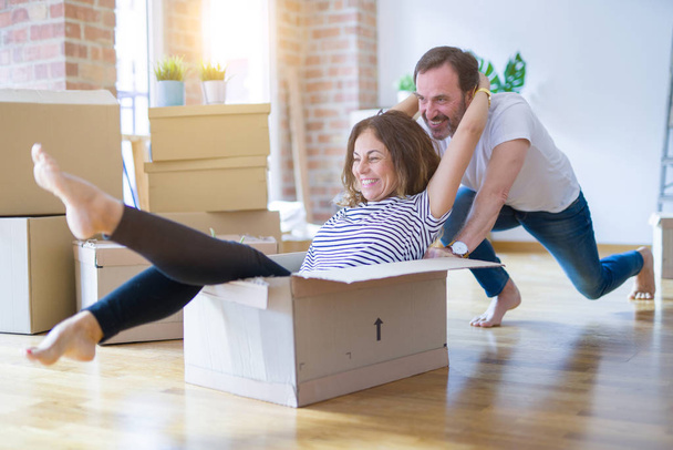 Старшие романтические пары среднего возраста весело катаются внутри картона, взволнованные и улыбающиеся счастливы для переезда в новый дом
 - Фото, изображение