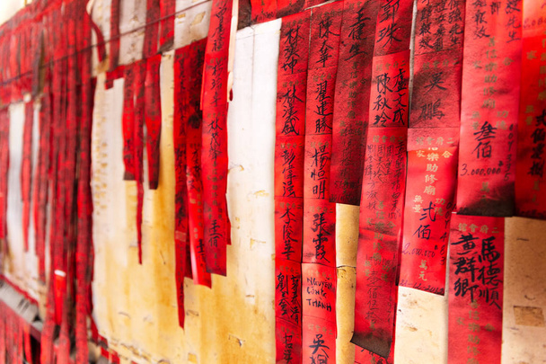 Banderas de oración de papel rojo o hojas de oración con nombres en tinta negra china en la pagoda Ong Bon (Nhi Phu MIeu), Cho Lon, Saigón, Ciudad Ho Chi MInh, Vietnam
. - Foto, imagen