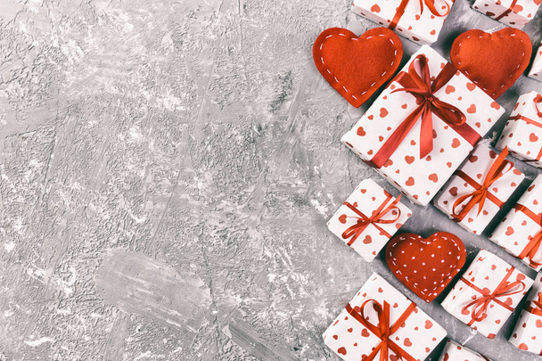 Валентина или другой праздник ручной работы подарок в бумаге с красными сердцами и подарочной коробке в праздничной обертке. Подарочная коробка на сером цементном столе вид сверху с копировальным пространством, пустое место для дизайна
 - Фото, изображение