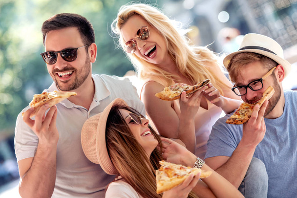 Vrienden met plezier en het eten van pizza in de stad. Mensen, eten, vriendschap en lifestyle concept. - Foto, afbeelding