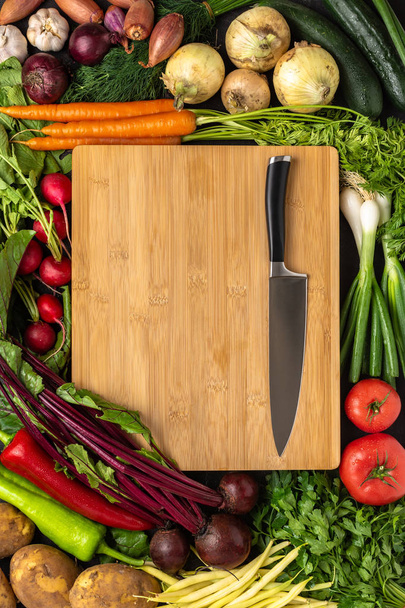 Kochmesser auf Holzschneidebrett mit frischem Gemüse Hintergrund. Konzept der gesunden Ernährung. - Foto, Bild