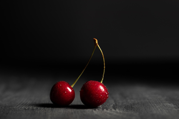 red delicious cherries with water drops on wooden table isolated on black - Photo, Image
