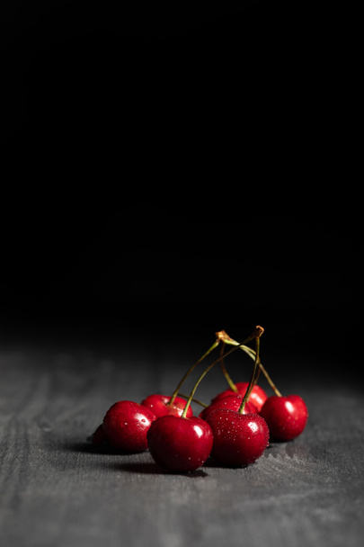 red tasty cherries with water drops on wooden table isolated on black - Zdjęcie, obraz