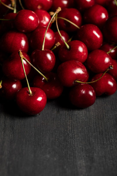 red delicious cherries scattered on wooden dark table - Foto, afbeelding