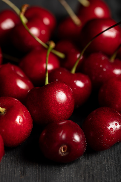close up view of red delicious and ripe cherries with water drops on wooden table - Photo, Image
