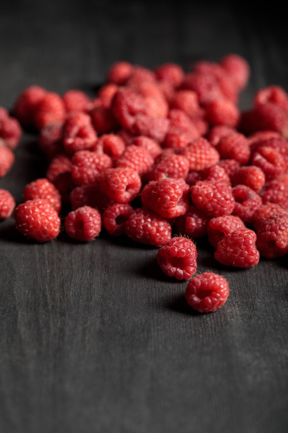 selective focus of delicious ripe raspberries scattered on wooden table - Foto, Bild