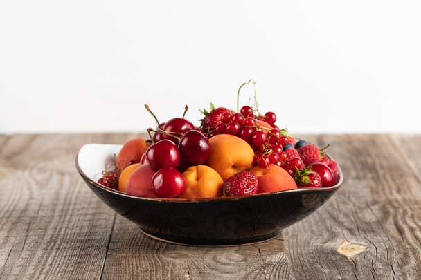 plate with mixed delicious ripe berries on wooden table isolated on white - Foto, Bild