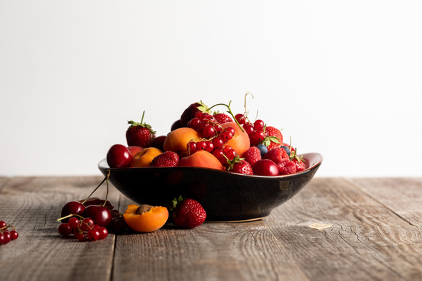 Teller mit gemischten köstlichen reifen Beeren auf Holztisch isoliert auf weiß - Foto, Bild