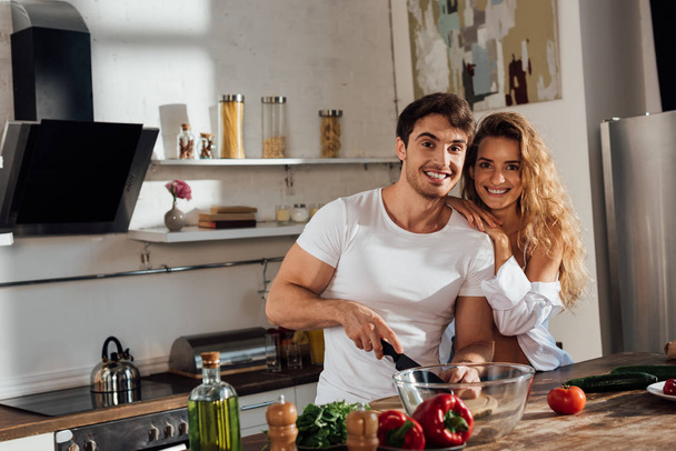 sexy couple smiling while cooking together in kitchen - Foto, Bild